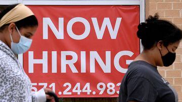 In this file photo taken on August 16, 2021, women walk past by a &quot;Now Hiring&quot; sign outside a store in Arlington, Virginia.