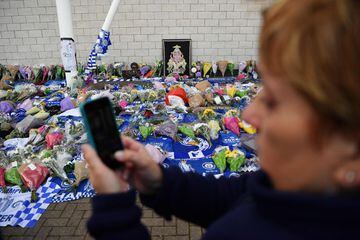 A woman uses a smartphone in front of tributes outside Leicester City Football Club's King Power Stadium in Leicester