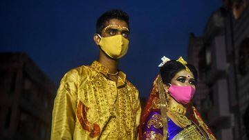 A groom and a bride (R) wearing facemasks wait to perform rituals of their social marriage funtion, during a lockdown imposed by the state government against the surge in COVID-19 coronavirus cases, in Kolkata on July 29, 2020. (Photo by Dibyangshu SARKAR