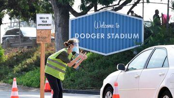 A volunteer wearing facemask and face shield checks for Covid-19 test appointments from motorists arriving at Dodger Stadium in Los Angeles, California. 