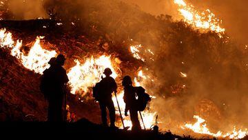 Firefighters watch backfires used to slow the spread of the Caldor Fire in Grizzly Flats, California, August 22, 2021. 
