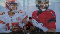 Tampa (United States), 03/02/2021.- A passer-by poses in front of a fence banner with the portraits of Super Bowl LV quarterback Patrick Mahomes (L) and Tom Brady, ahead of the NFL Super Bowl LV in Tampa, Florida, USA, 04 February 2021. The AFC Champion K