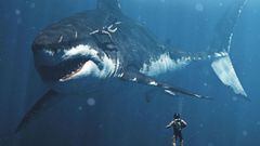 Dos buceadores interact&uacute;an con un megalod&oacute;n, un tibur&oacute;n gigante, bajo el agua. 