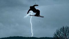 Lukas M&uuml;llauer en un salto con esqu&iacute;s con un rel&aacute;mpago al fondo y el cielo nublado. 