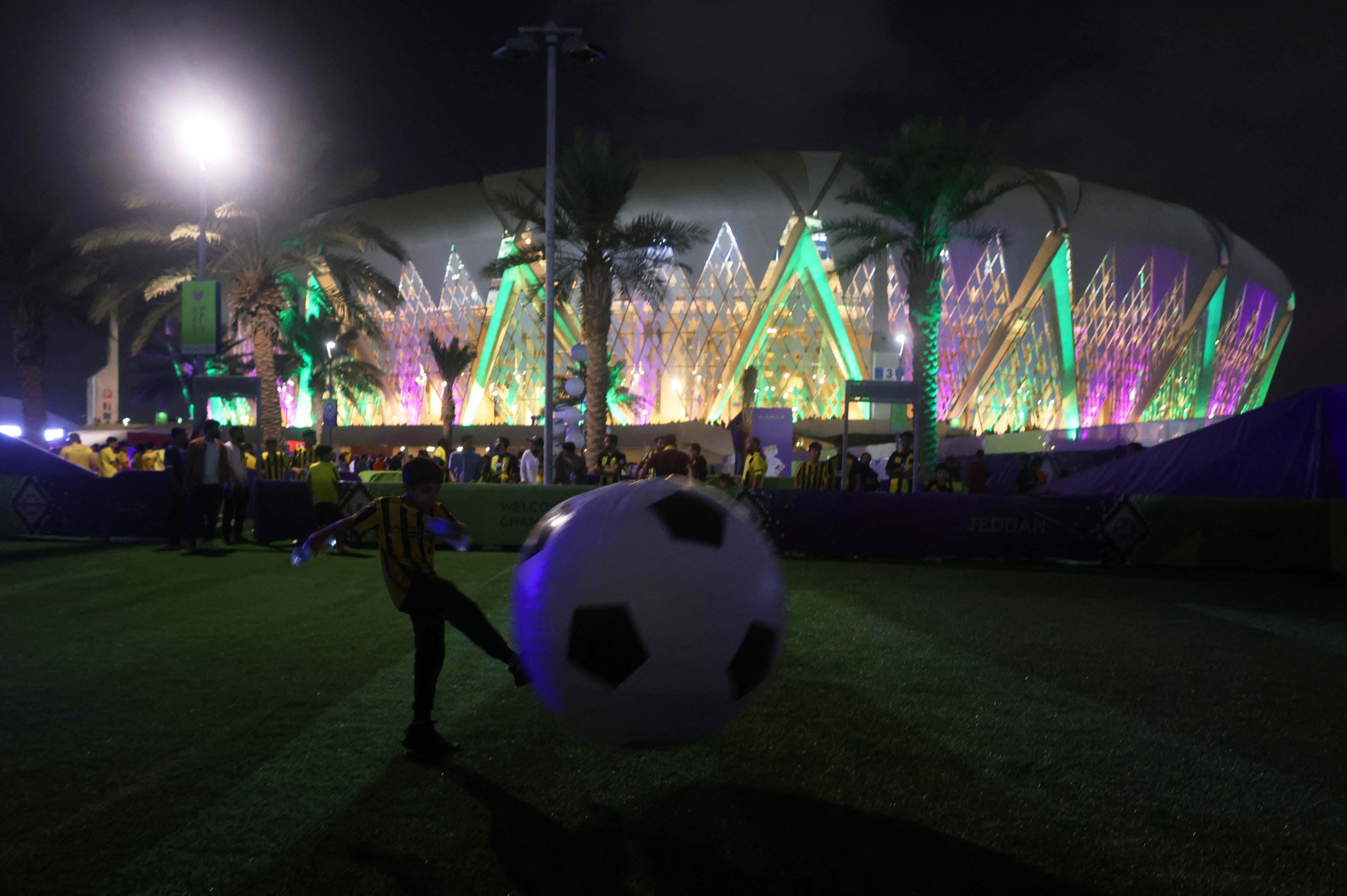 Soccer Football - Club World Cup - First Round - Al Ittihad v Auckland City - King Abdullah Sports City, Jeddah, Saudi Arabia - December 12, 2023 A young fan plays with a inflatable football outside the stadium before the match REUTERS/Amr Abdallah Dalsh