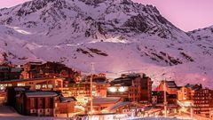 Val Thorens, pueblo y estación de esquí, iluminado de noche con la montaña nevada al fondo.