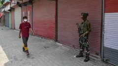 13 July 2020, India, Kashmir: A man wears a protective face mask walks past a paramilitary trooper standing on guard during a lockdown re-imposed to prevent the spread of coronavirus. Photo: Saqib Majeed/SOPA Images via ZUMA Wire/dpa
 
 
 13/07/2020 ONLY 