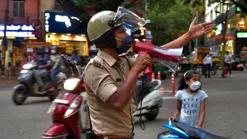 A police officer uses a loud speaker to warn and disperse people gathered in a commercial area in Bangalore.