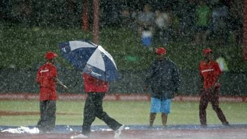 A worker holds an umbrella on the pitch after the first ODI cricket match between England and South Africa was stopped due to rain in Bloemfontein, South Africa.