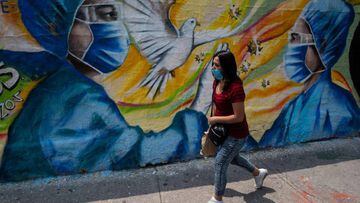 A woman walks past a coronavirus-related mural painted by urban artist Alejandro Bautista Torres, 38, aka Kato, in Mexico City, on May 23, 2020, during the novel COVID-19 pandemic. (Photo by Pedro PARDO / AFP)