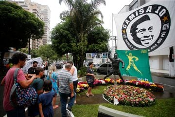 Los aficionados visitan una estatua de la leyenda del fútbol brasileño Pelé en Santos mientras la gente llora su muerte.