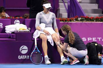 Garbine Muguruza of Spain has her knee strapped by a physiotherapist during the final of the women's singles at the Qatar Open tennis competition in Doha, on February 18, 2018. / AFP PHOTO / KARIM JAAFAR