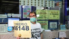 Javier Muñoz, empleado de la administración de Lotería en la estación del AVE de Atocha, muestra el numero del  primer premio, cuya administración vendió 129 series de este número.