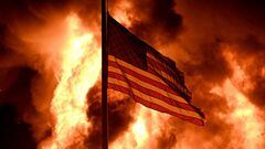 Las llamas envuelven el edificio de la Divisi&oacute;n de Correcciones Comunitarias mientras una bandera estadounidense ondea en un poste y las protestas se convierten en incendios en Kenosha, Wisconsin, EE. UU. El 24 de agosto de 2020.
