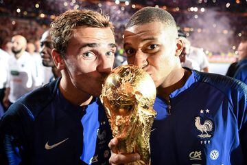 Los jugadores franceses Antoine Griezmann y Kylian Mbappé besan la Copa del Mundo de 2018.