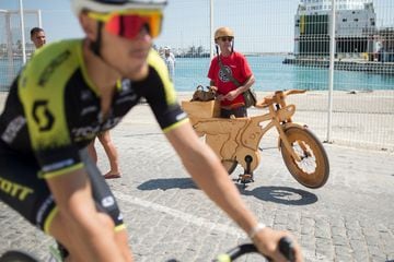 Un aficionado al ciclismo observa la carrera con su bicicleta de madera que tiene un mapa de España, en el que vemos el recorrido de la Vuelta.