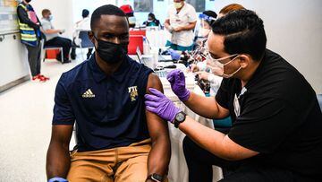 Pharmacy student Jason Rodriguez (R) administers a Covid-19 vaccine to Larry Grier at the Christine E. Lynn Rehabilitation Center in Miami, Florida on April 15, 2021. - Jackson Health System launched a Covid-19 vaccination initiative with colleges and uni