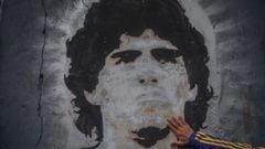 FILED - 25 November 2020, Argentina, Buenos Aires: A fan of the football club Boca Juniors puts his hand on a mural with the picture of the football star Diego Maradona on the day of his death. Argentina football great Diego Maradona has died at the age o