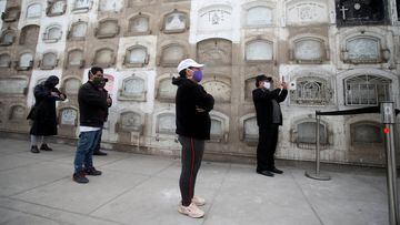 LIMA, PERU - JUNE 04: Relatives wearing face masks pray and film with their mobile phones the funeral of Maria Polo, 72, at El Angel Cemetery on June 4, 2020 in Lima, Peru. Peru is the second country in South America with most cases of COVID-19, only after Brazil. President Vizcarra extended lockdown to halt spread of the virus until June 30. (Photo by Raul Sifuentes/Getty Images)