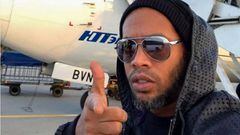 Ronaldinho en la pista de un aeropuerto haciendo el gesto de disparar con su mano.