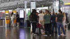 Travelers use a self-service check-in kiosk while other passengers queue at a customer service center for Deutsche Lufthansa AG at Terminal 1 of Frankfurt Airport in Frankfurt, Germany, on Friday, June 24, 2022. Lufthansa canceled 2,200 flights after a wave of coronavirus infections worsened staffing shortages, adding to Europes travel chaos as the crucial summer vacation period gets under way. Photographer: Alex Kraus/Bloomberg via Getty Images