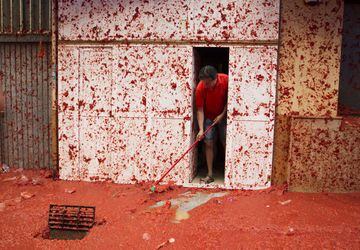 A man cleans his front door during the annual "Tomatina" festival in the eastern town of Bunol, on August 30, 2017.
The iconic fiesta -- which celebrates its 72nd anniversary and is billed at "the world's biggest food fight" -- has become a major draw for foreigners, in particular from Britain, Japan and the United States. / AFP PHOTO / JAIME REINA