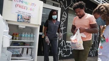 MIAMI, FLORIDA - AUGUST 21: (L-R) Sherina Jones, Danny Agnew and Valentina Pedon, 9, place items into the community refrigerator that Sherina Jones set up in front of the Roots Collective store on August 21, 2020 in Miami, Florida. The fridge is set up to