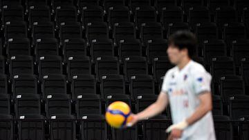 A player prepares to serve a ball in front of empty seats at Ariake Arena in Tokyo on July 23, 2021, ahead of the start of the Tokyo 2020 Olympic Games. (Photo by Angela Weiss / AFP)