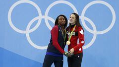 Simone Manuel y Penny Oleksiak  posan en lo m&aacute;s alto del podium con sus medallas de oro logradas en la prueba de 100 metros libres femenino de nataci&oacute;n.
