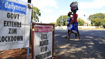 Harare (Zimbabwe), 02/05/2020.- Two women walk past a couple of roadside signs displaying the main headlines for the Zimbabwean dailies &#039;The Herald&#039; (R): &#039;Face Masks Now Mandatory&#039; and &#039;dailynews&#039; (L): &#039;Gov&#039;t Extend