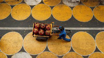 A man pushes a cart filled with liquefied petroleum gas (LPG) cylinders on a street painted with circles for people to maintain social distancing after a few restrictions were relaxed during an extended lockdown to slow the spread of the coronavirus disea