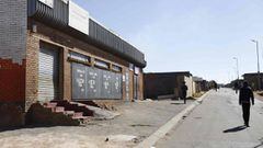 People walk past a closed liquor shop is seen in Soweto, on July 13, 2020. - South African President Cyril Ramaphosa on July 12, 2020 re-imposed a night curfew and suspended alcohol sales as COVID-19 coronavirus infections spiked and the health system ris
