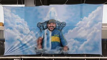 (FILES) In this file photo taken on March 14, 2021 a banner with an image of late Argentine football icon Diego Maradona is seen during the Argentine Professional Football League Superclasico match between Boca Juniors and River Plate at La Bombonera stadium in Buenos Aires. - The public prosecutor&#039;s office investigating Argentine football star Diego Maradona&#039;s death postponed on May 28, 2021 for June 14 the beginning of the hearings of seven people suspicious of having &quot;abandoned him to his fate&quot;, which were scheduled to start on May 31. (Photo by Alejandro PAGNI / POOL / AFP)