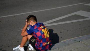 A kid sporting Barcelona&#039;s Argentinian forward Lionel Messi&#039;s jersey sits on the pavement outside the Barcelona&#039;s Ciutat Esportiva Joan Gamper in Sant Joan Despi waiting for the arrival of Barcelona players to undergo a medical test for COV