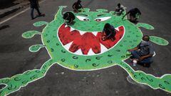 Mumbai (India), 10/05/2020.- Indian artists paints a graffiti on a road showing a stylized COVID-19 virus on the roadside amid the nationwide coronavirus lockdown, in Mumbai, India, 10 May 2020. The Indian government announced lockdown extension for two w