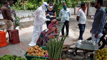 A healthcare worker wearing personal protective equipment (PPE) takes a swab from a vegetable vendor to test her for the coronavirus disease (COVID-19) at a roadside market in Ahmedabad, India, July 7, 2020. REUTERS/Amit Dave