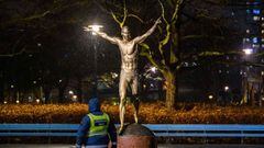 27 November 2019, Sweden, Malmo: A man passes by the Statue of Swedish footballer Zlatan Ibrahimovic which has been vandalized by a blue sheet and a toilet seat in front of Malmo&#039;s Stadion. Ibrahimovic has sparked anger among fans of his former club 