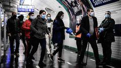 (FILES) In this file photo taken on May 14, 2020, commuters wearing facemasks walk at the Saint-Lazare platform of line 13 metro station in Paris during the ease of lockdown measures taken to curb the spread of the COVID-19. - Masks will no longer be mand