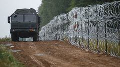 FILE PHOTO: A view of a vehicle next to a fence built by Polish soldiers on the border between Poland and Belarus near the village of Nomiki, Poland August 26, 2021. REUTERS/Kacper Pempel/File Photo