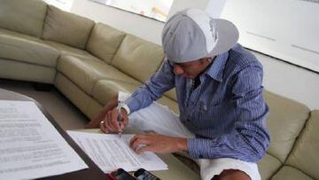 Neymar signs his fanous name onto some paper.