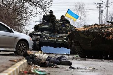 Ukrainian army soldiers sit on the top of their tank as a body of a civilian, who according to residents was killed by Russian army soldiers, lies on the street, amid Russia's invasion of Ukraine, in Bucha, in Kyiv region, Ukraine April 2, 2022.