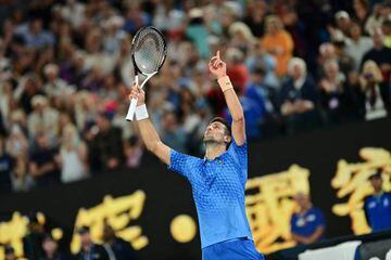 Novak Djokovic celebra su victoria en la final del Open de Australia en el terreno de juego señalando al cielo.
