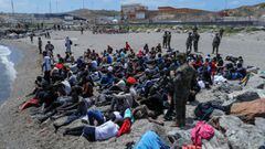 Spanish legionnaires stand around Moroccan citizens, after thousands of Moroccans swam across Spanish-Moroccan border on Monday, in Ceuta, Spain, May 18, 2021. REUTERS/Jon Nazca