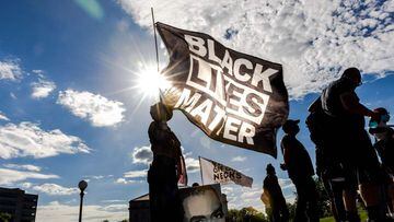 Una mujer sostiene una bandera Black Lives Matter durante un evento en memoria de George Floyd y para pedir justicia para aquellos que perdieron a sus seres queridos por la violencia policial fuera del Capitolio del Estado de Minnesota el 24 de mayo de 2021 en Saint Paul, Minnesota. 