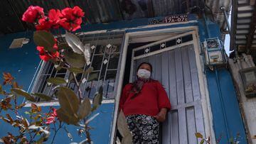 Mujer de escasos recursos parada en la puerta de su casa