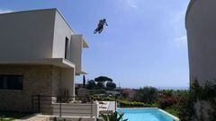 Fabio Wibmer saltando con su bici de street trial a una piscina de una casa, desde un tejado. 