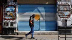 A man walks past a shutter of a closed store painted with the Argentinian flag and graffiti depicting Diego Maradona and Lionel Messi, after CONMEBOL announced Argentina pulled out hosting the Copa America, in Buenos Aires, Argentina May 31, 2021. REUTERS/Agustin Marcarian