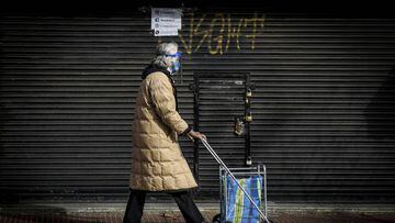 BUENOS AIRES, ARGENTINA - JULY 02: A woman wearing a plastic protective mask passes with a shopping cart in front of a closed shop at Avenida Avellaneda on July 2, 2020 in Buenos Aires, Argentina. According to the national statistics bureau (INDEC), economy in Argentina shrank 26% year on year in April, the first full month of coronavirus lockdown. Due to increasing number of cases in Buenos Aires Aires and its metropolitan area, authorities tightened restrictions allowing only essential shops and industries to remain open to public. Apart from dealing with the pandemic, Argentina is on default and holds a negotiation with creditors to restructure a 66 billion USD debt. (Photo by Marcelo Endelli/Getty Images)