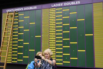 Tennis - Wimbledon - All England Lawn Tennis and Croquet Club, London, Britain - June 28, 2021 Spectators take a photo in front of an order of play board before the start of play REUTERS/Toby Melville