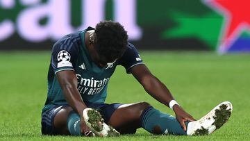 Bukayo Saka, jugador del Arsenal, se sienta en el césped tras sufrir una lesión muscular ante el Lens.